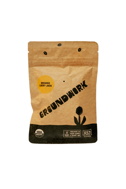 A brown Groundwork Coffee bag labeled Coffee Sample features minimalist black graphics and certification logos from their Signature Blends collection.