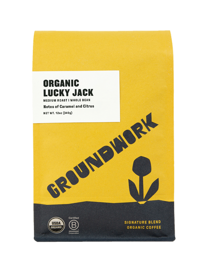 A 12 oz yellow and gray bag of Groundwork Coffee Lucky Jack Medium Roast whole bean, with caramel and citrus notes and coffee certifications.