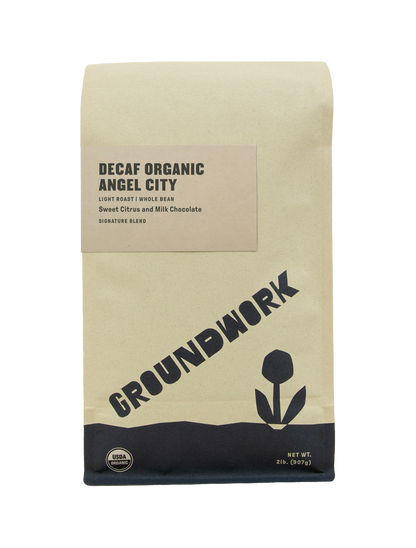 A brown bag of Groundwork Coffees Decaf Angel City features a minimalist flower design, highlighting its light roast whole beans with sweet citrus and milk chocolate notes.